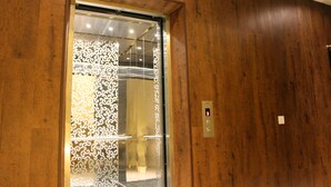 An elevator with a wooden wall and a decorative metal panel. - Hotel Time Nilai (Nilai)