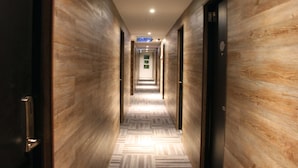 A hallway with wooden walls and patterned flooring, leading to a reception area with a sign. - Hotel Time Nilai (Nilai)