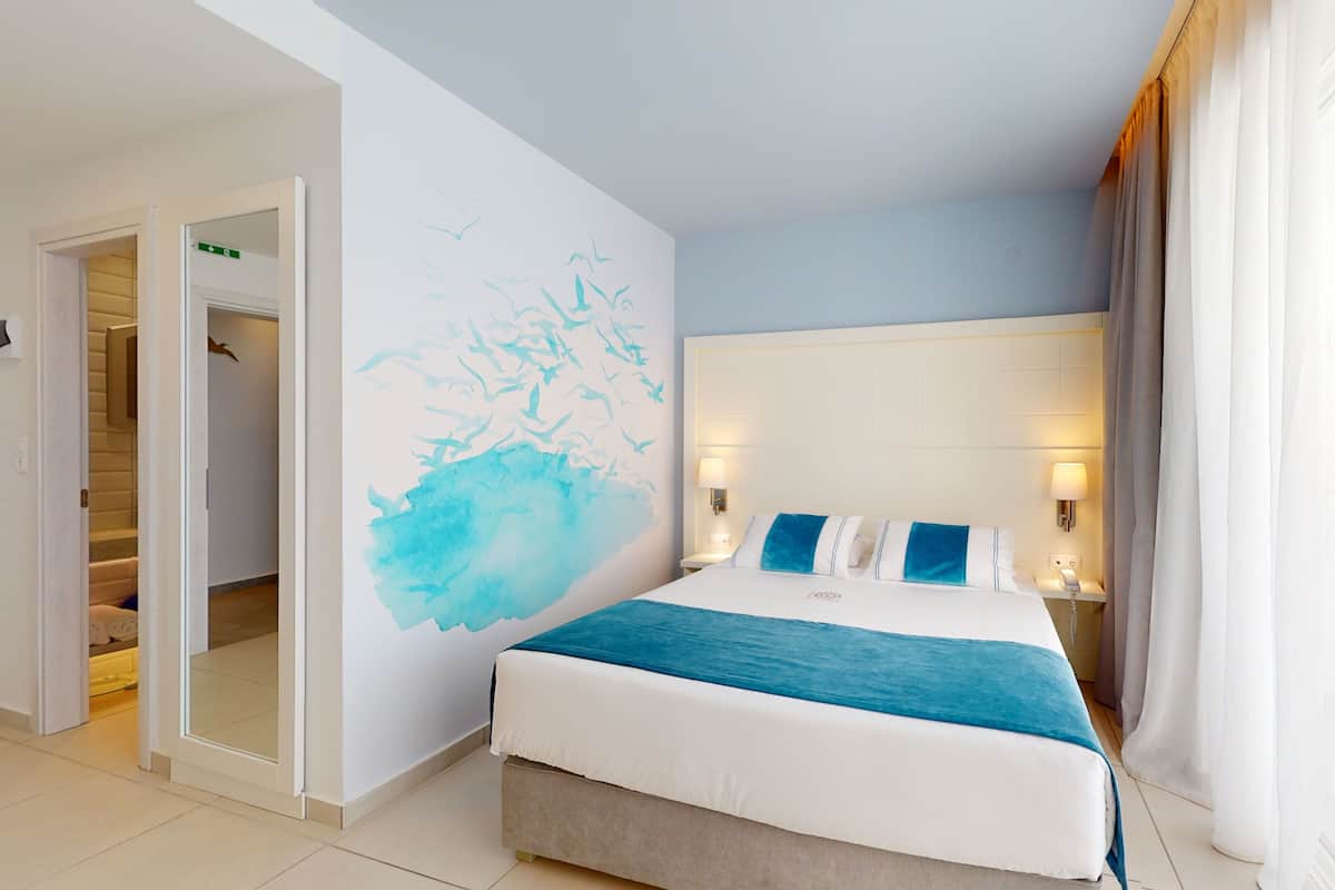 Ein Hotelzimmer mit einem großen Bett, einem Wandbild und einer Tür zu einem Badezimmer.