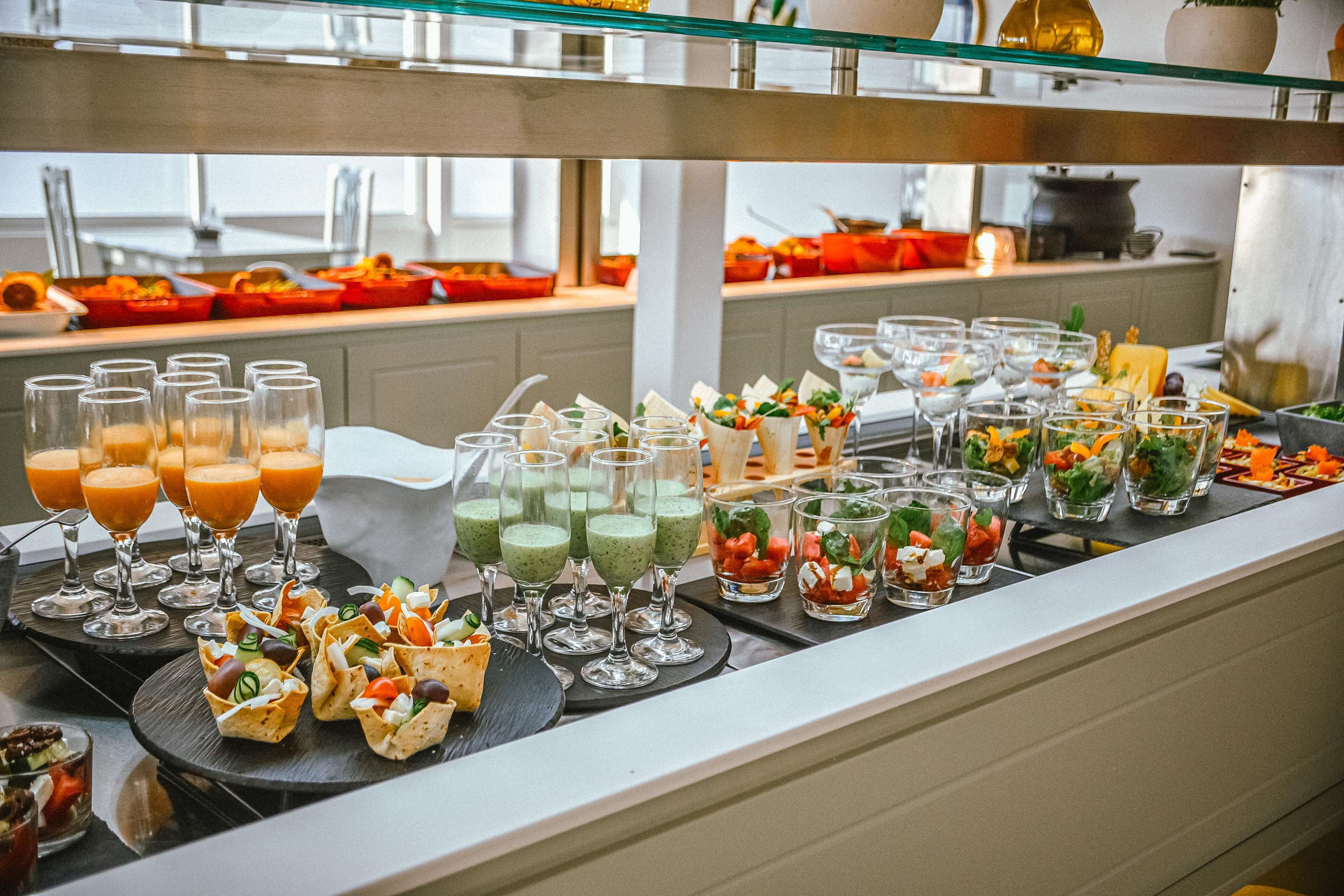 Ein reichhaltiges Buffet mit verschiedenen Speisen und Getränken, darunter Smoothies, Salate und Vorspeisen.