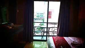 Una habitación de hotel con una cama, un escritorio con teléfono y un balcón con sillas.