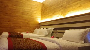 Una habitación de hotel con paredes de madera, dos camas con ropa blanca y un cabecero a rayas.