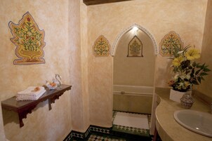 Casa de banho com banheira, pia e azulejos decorativos.