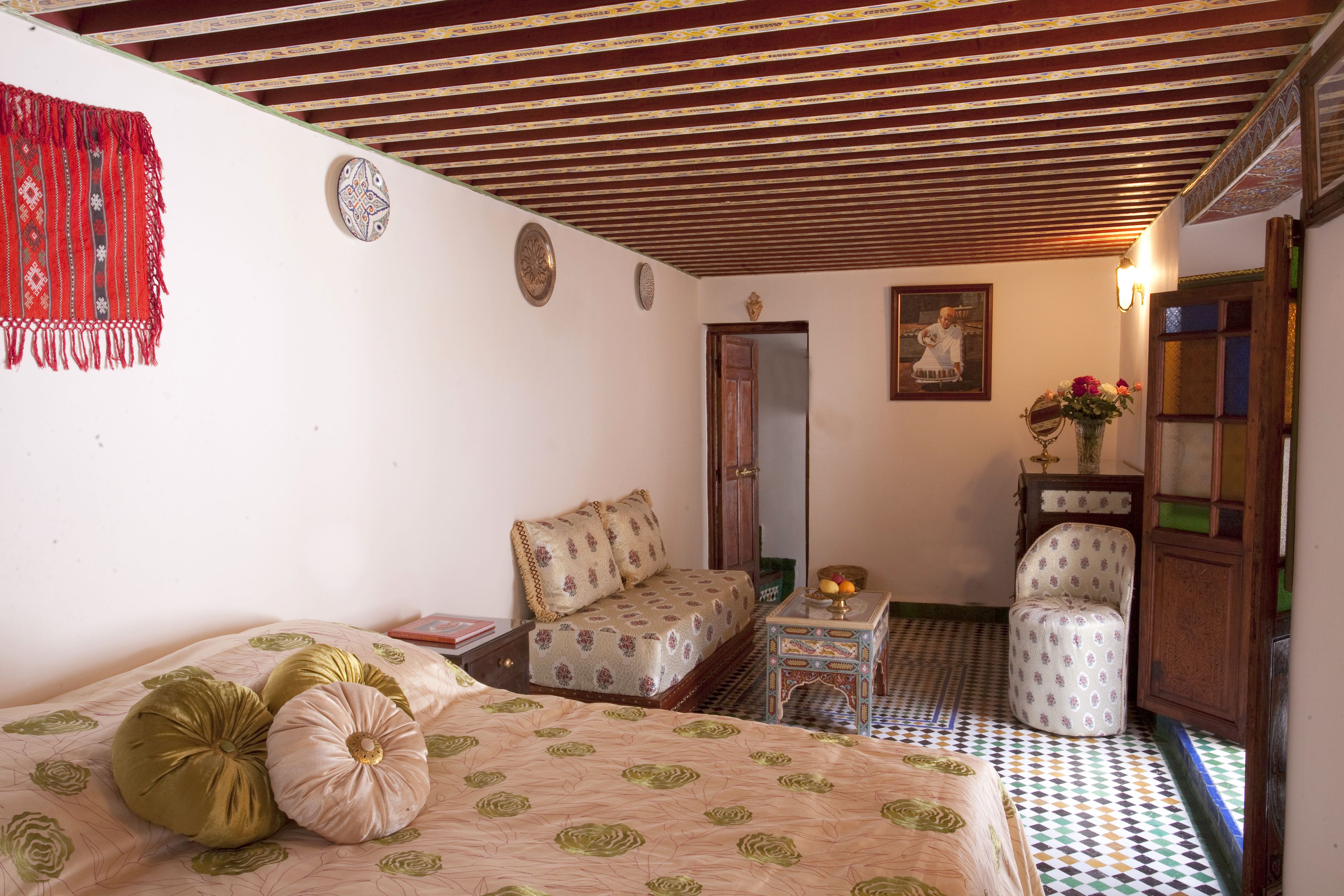 Un dormitorio con cama, una silla, una mesita y un espejo.