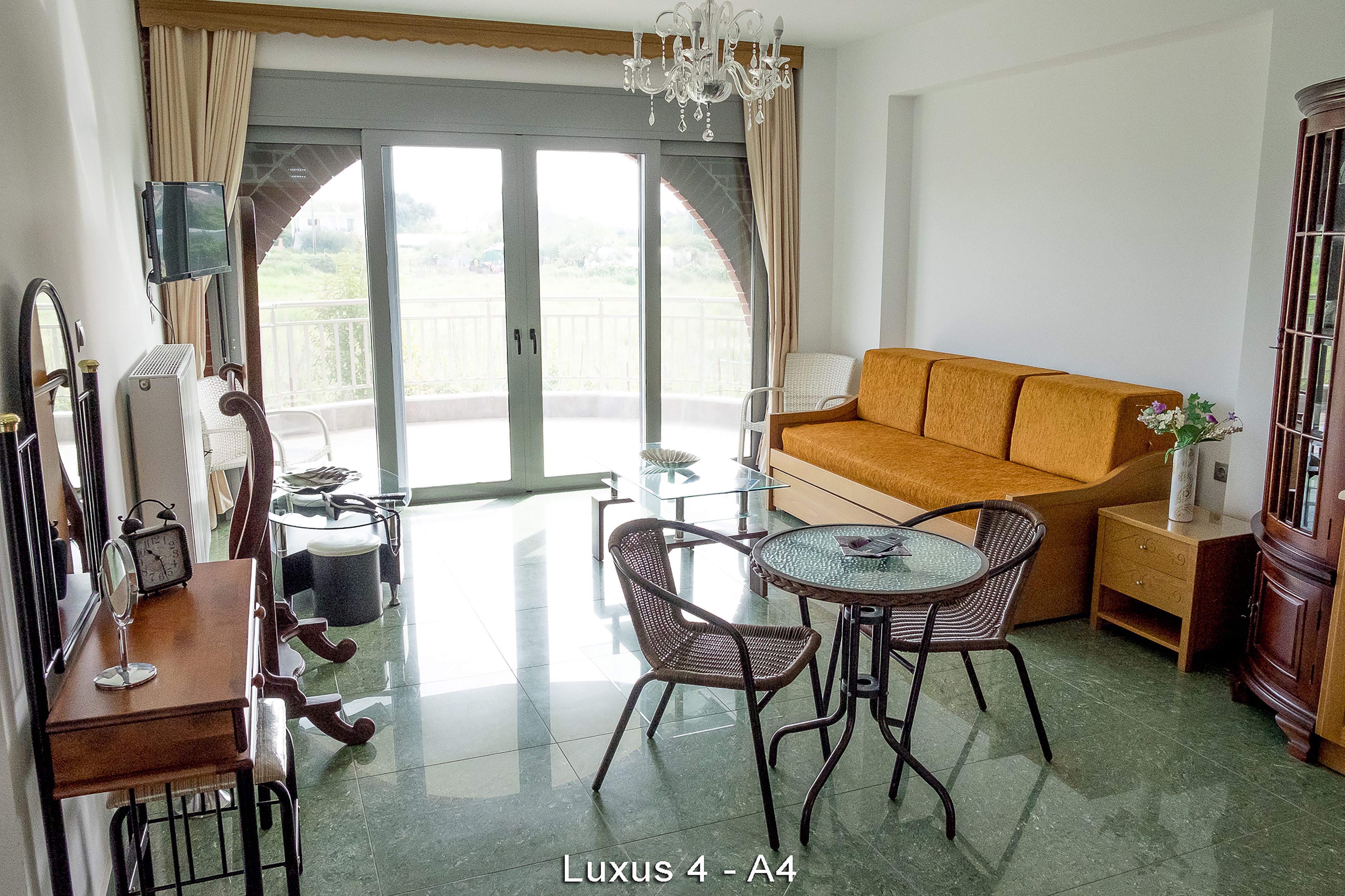 Un vaste espace de vie comprenant un canapé, une table à manger avec des chaises, un téléviseur fixé au mur et une grande porte-fenêtre coulissante donnant sur un balcon extérieur.