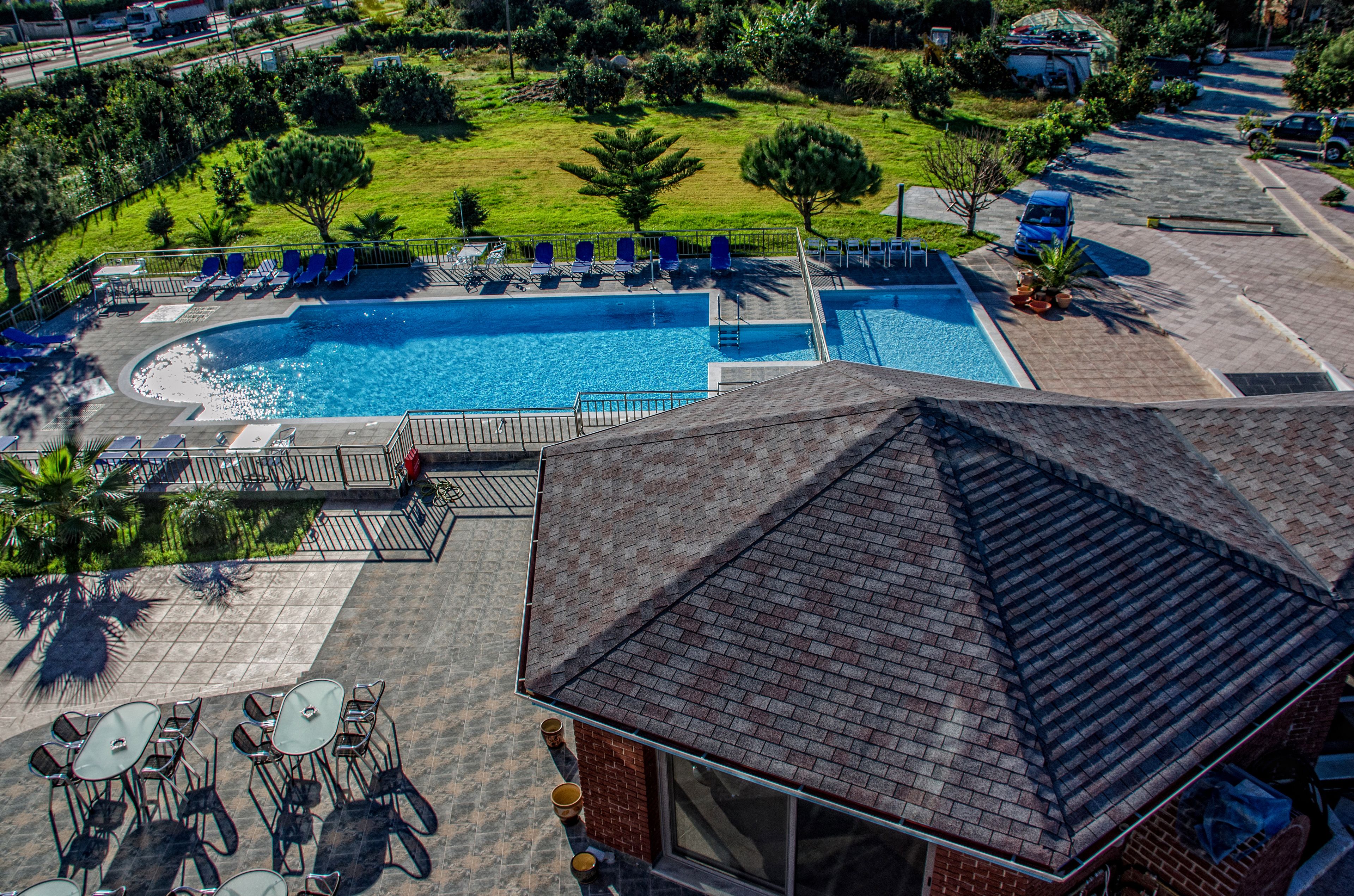 Uma área de piscina no terraço com espreguiçadeiras e um pequeno pátio com mesas e cadeiras.