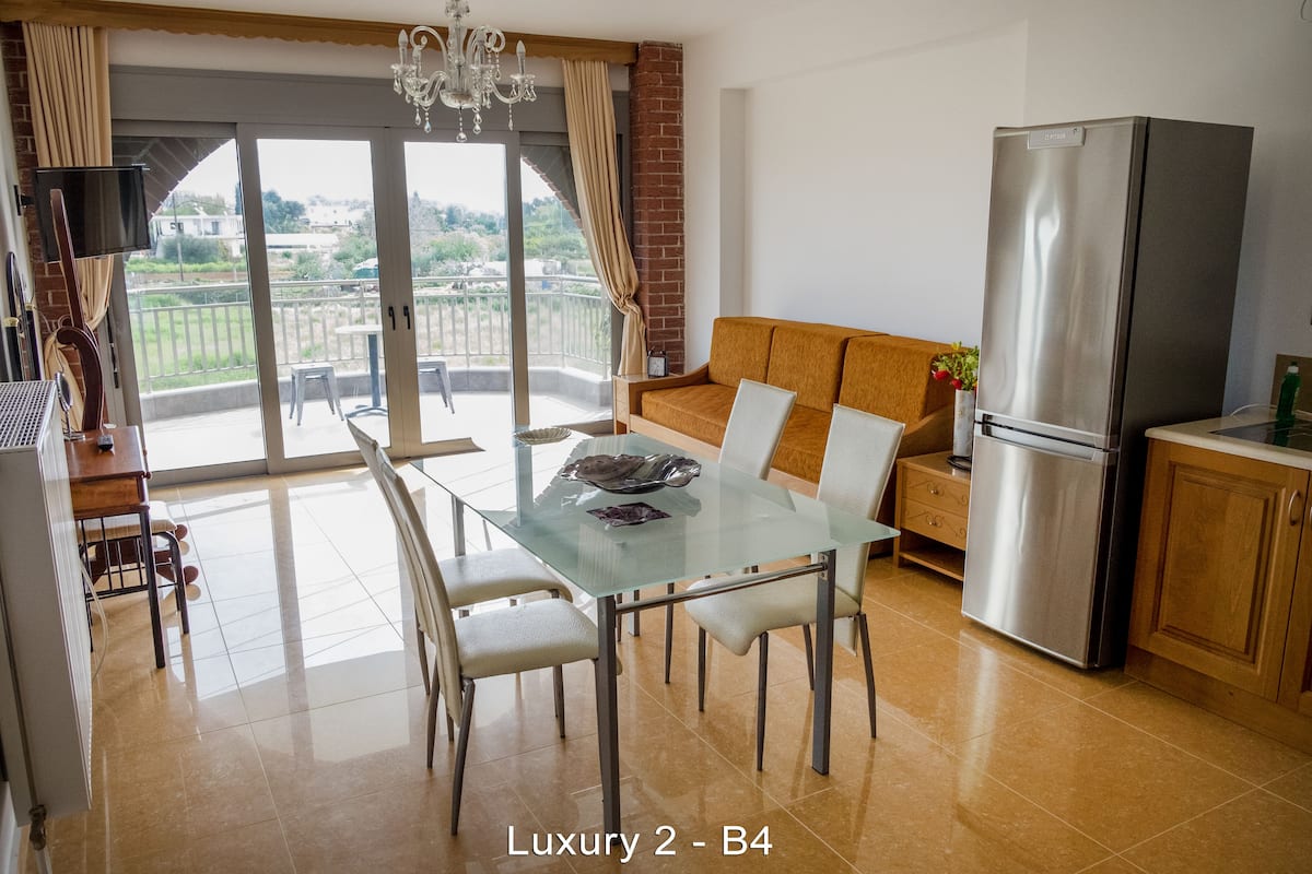 A modern kitchen with a dining area, a sofa, and a large refrigerator.