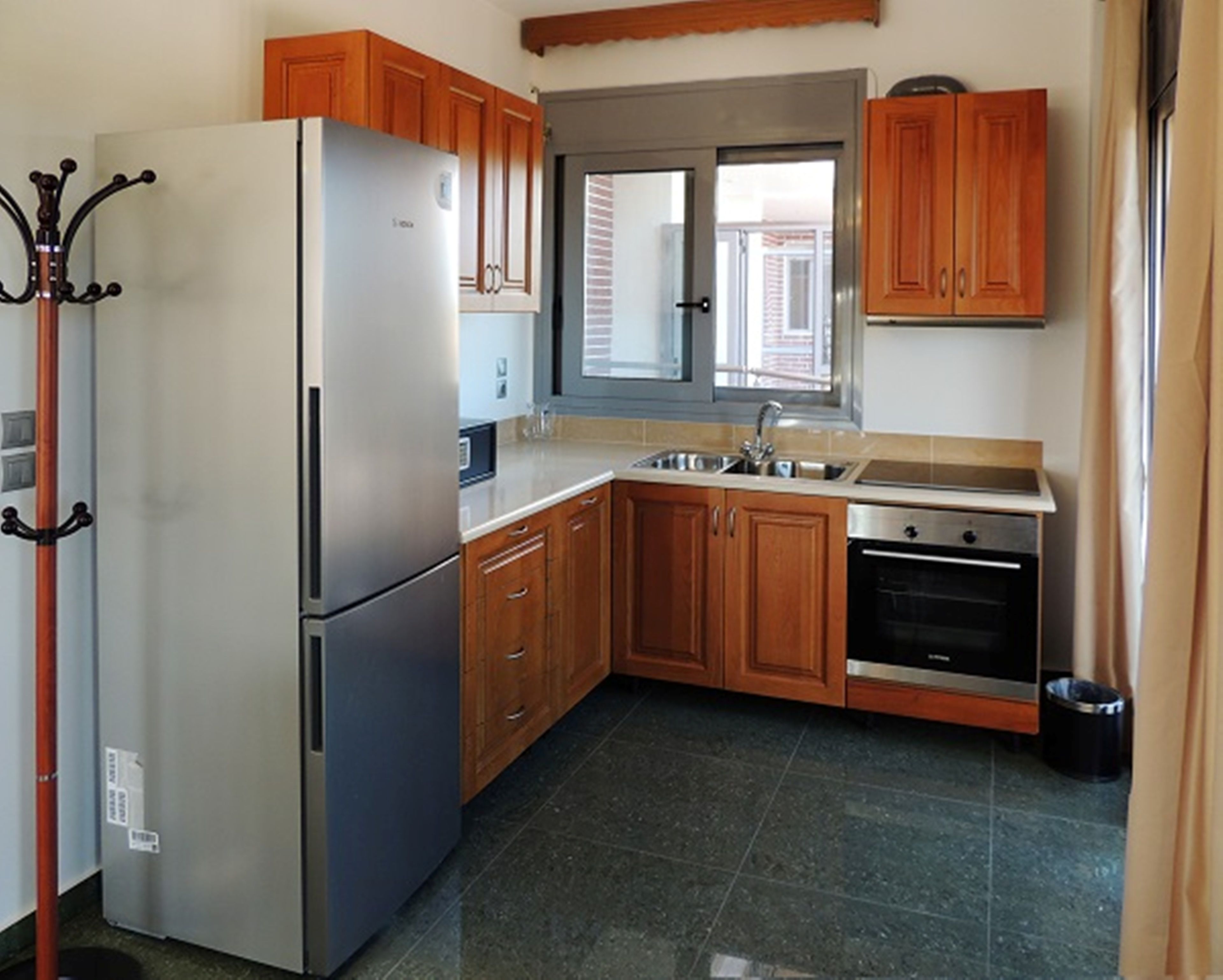 Una cocina con armarios de madera, un refrigerador de acero inoxidable, un lavamanos doble y un horno empotrado.