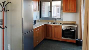 Una cocina con armarios de madera, un refrigerador de acero inoxidable, un lavamanos doble y un horno empotrado.
