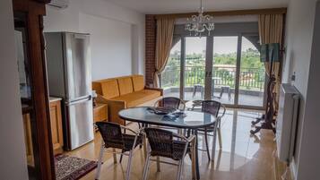 Una sala de estar moderna con sofá, mesa de comedor, sillas y vistas al exterior.