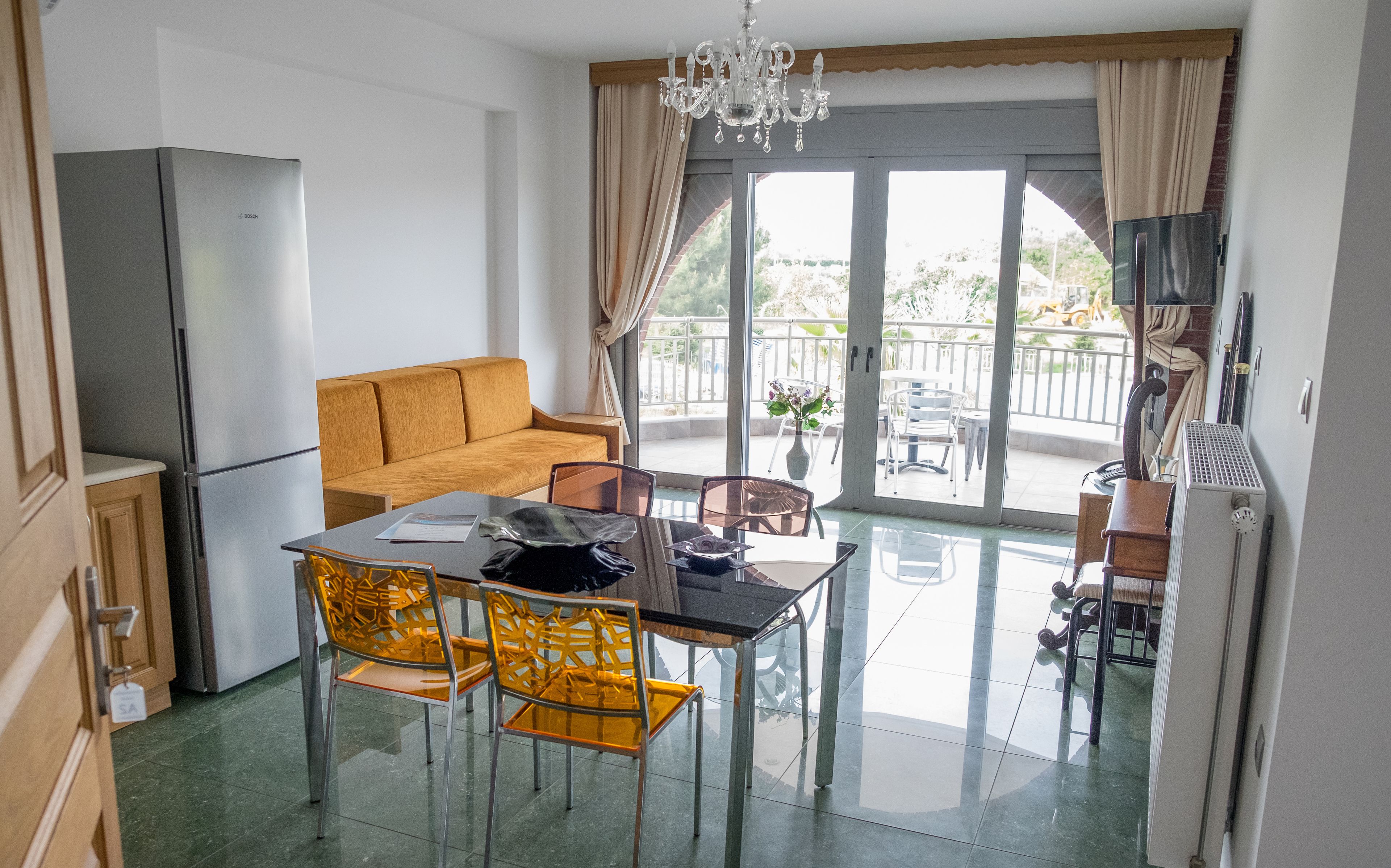 Un espacio habitable compacto con kitchenette, comedor con mesa y sillas, sofá y balcón con vistas.