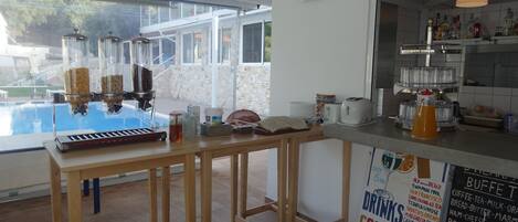 Zona de bar con mostrador de madera, un piano y un cartel que enumera bebidas y cócteles.