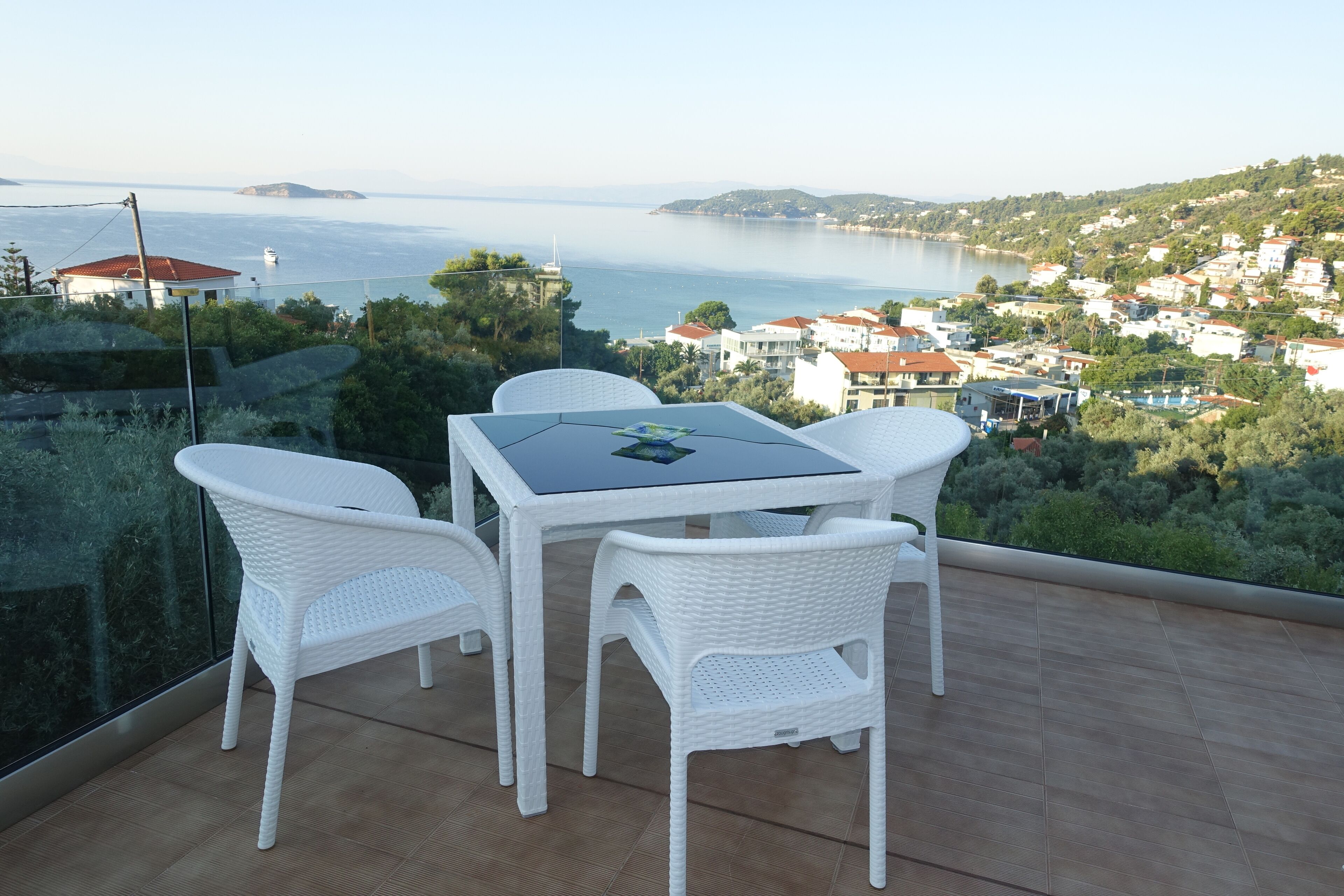 A terrace with a table and chairs overlooking a coastal town.