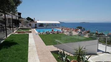 Zona de piscina con vistas despejadas al mar, un área de estar cubierta y un camino que lleva a la piscina.