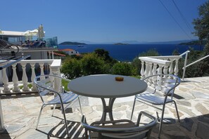 A terrace with a stone floor, white balustrade, and a round table with two chairs.