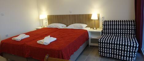 A hotel room with a bed, two bedside lamps, a chair, and a window with curtains.