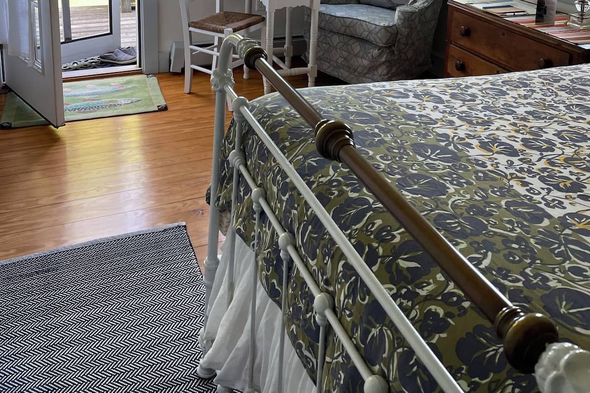 Una camera da letto con un letto, una sedia, un tavolino e una finestra con persiane.