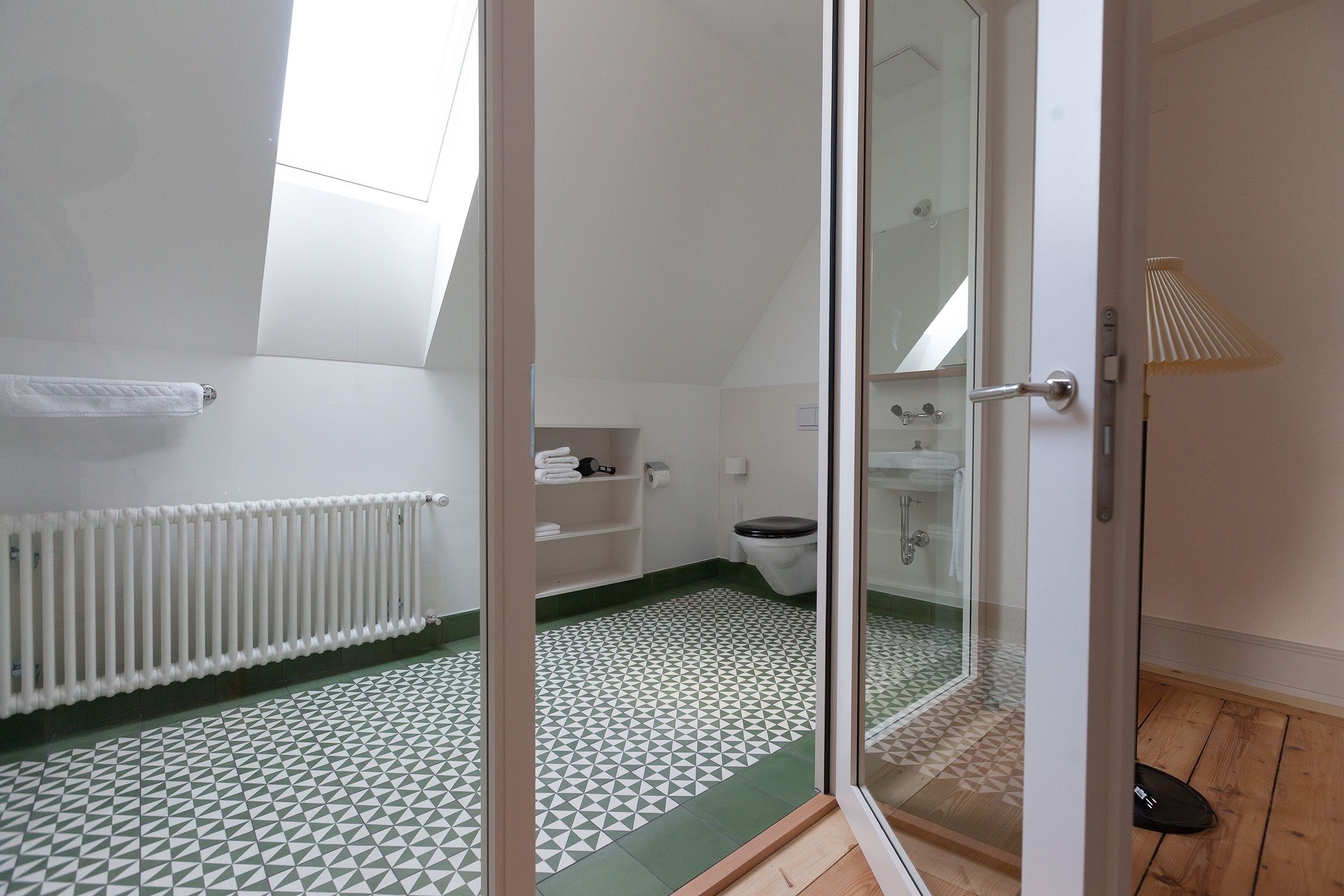 A small, modern bathroom with a shower, toilet, and radiator.