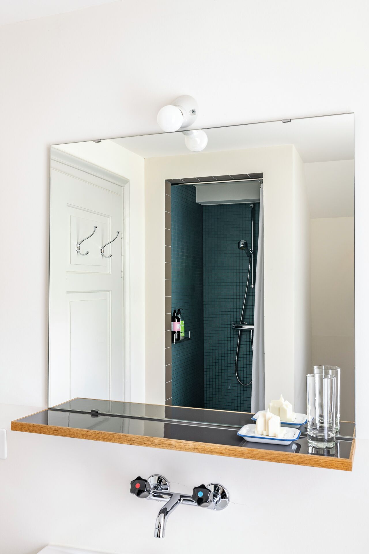 Une salle de bain dotée d’un grand miroir, d’une douche et d’une coiffeuse avec un plateau en verre.