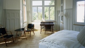 A bedroom with a bed, a piano, and two chairs. - Hotel Militärkantine (St. Gallen)