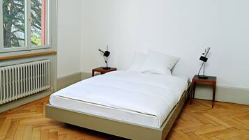 Ein Schlafzimmer mit einem Bett, zwei Nachttischen, einem Fenster und einer Heizung.