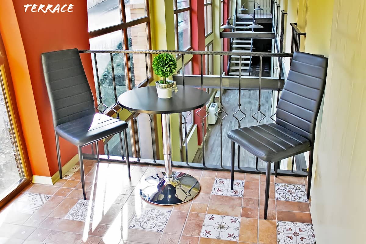 A private terrace with two black chairs, a round table, and a potted plant.
