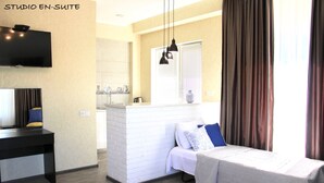 Un apartamento tipo estudio con cama, escritorio, televisor y kitchenette.