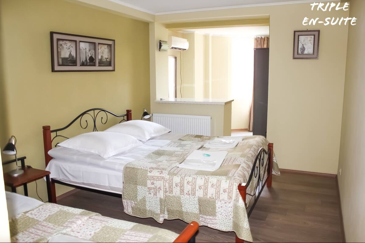 A room with two beds, a radiator, a mirror, and framed pictures on the wall.