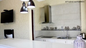 Una cocina moderna con una isla grande, un televisor de pantalla plana, luces colgantes y un salpicadero con baldosas de cerámica.