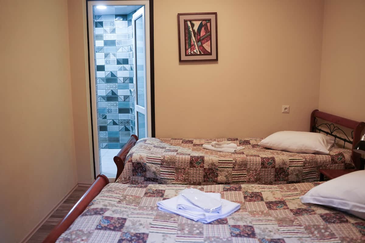 A bedroom with a bed, a window, and a painting on the wall.