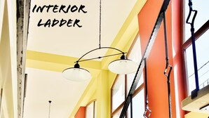 Un interior de varios niveles con un diseño de escalera único, ventanas amplias y lámparas colgantes.