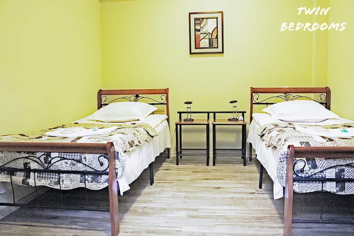 Twin bedrooms with two beds, a small table, and a wall-mounted picture.