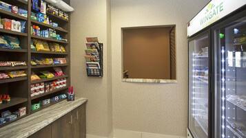 A snack shelf stocked with various items, a small window with a brown blind, and a Wingate frozen food display.