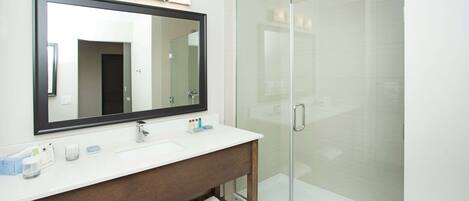 A modern bathroom with a large mirror, a white sink, and a glass shower enclosure.