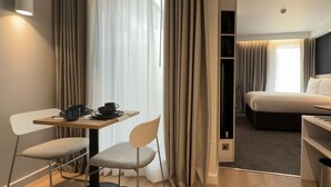 A hotel room with a bed, a desk with a chair, a table with a chair, and a wardrobe. - Holiday Inn Express London - Ealing by IHG (London)