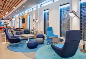 A modern lounge area with seating, tables, and large windows. - Holiday Inn Express London - Ealing by IHG (London)