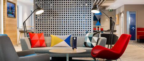 A modern lounge area with a sofa, armchairs, a coffee table, and a wall with a perforated design.