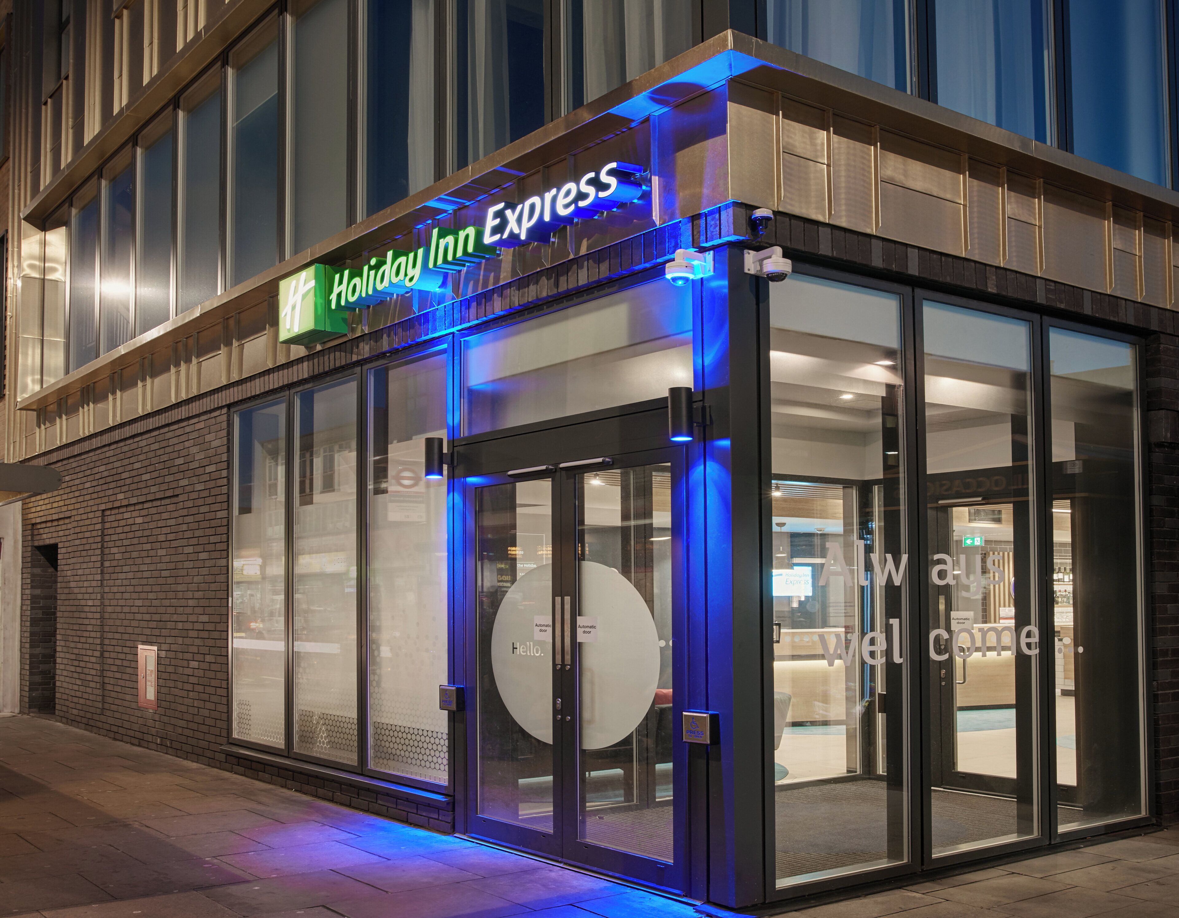 Eingangsbereich eines Holiday Inn Express Hotels mit automatischen Türen und einer Glasfassade.