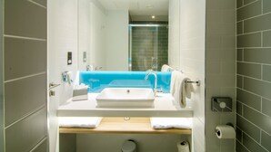 A modern bathroom with a white sink, blue accent wall, and a glass shower enclosure. - Holiday Inn Express London - Ealing by IHG (London)
