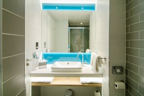 A modern bathroom with a white sink, blue accent wall, and a glass shower enclosure. - Holiday Inn Express London - Ealing by IHG (London)