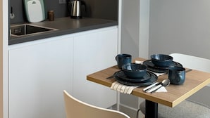 A kitchen with a dining table set with blue bowls, plates, and utensils. - Holiday Inn Express London - Ealing by IHG (London)