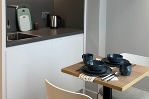 A kitchen with a dining table set with blue bowls, plates, and utensils. - Holiday Inn Express London - Ealing by IHG (London)