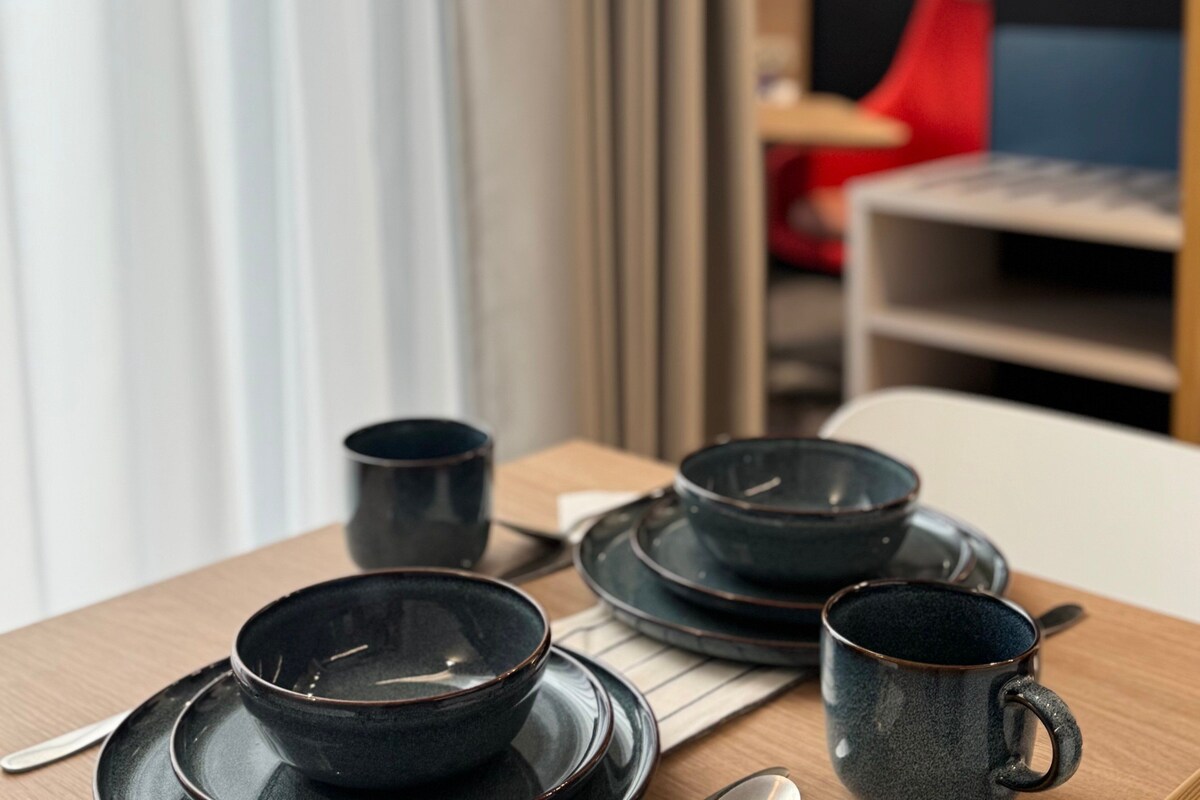 Una mesa con cuencos y platos negros, una cuchara y una taza.
