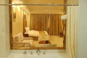 A hotel bathroom with a large mirror, a bathtub, and a shower curtain.