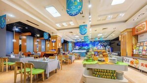 A restaurant with multiple dining tables and chairs, a counter with food items, and a blue aquarium in the background. - Fenghua International Garden Hotel (Dongying)