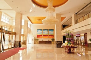 A spacious lobby with a red carpet, a chandelier, and a floral arrangement. - Fenghua International Garden Hotel (Dongying)