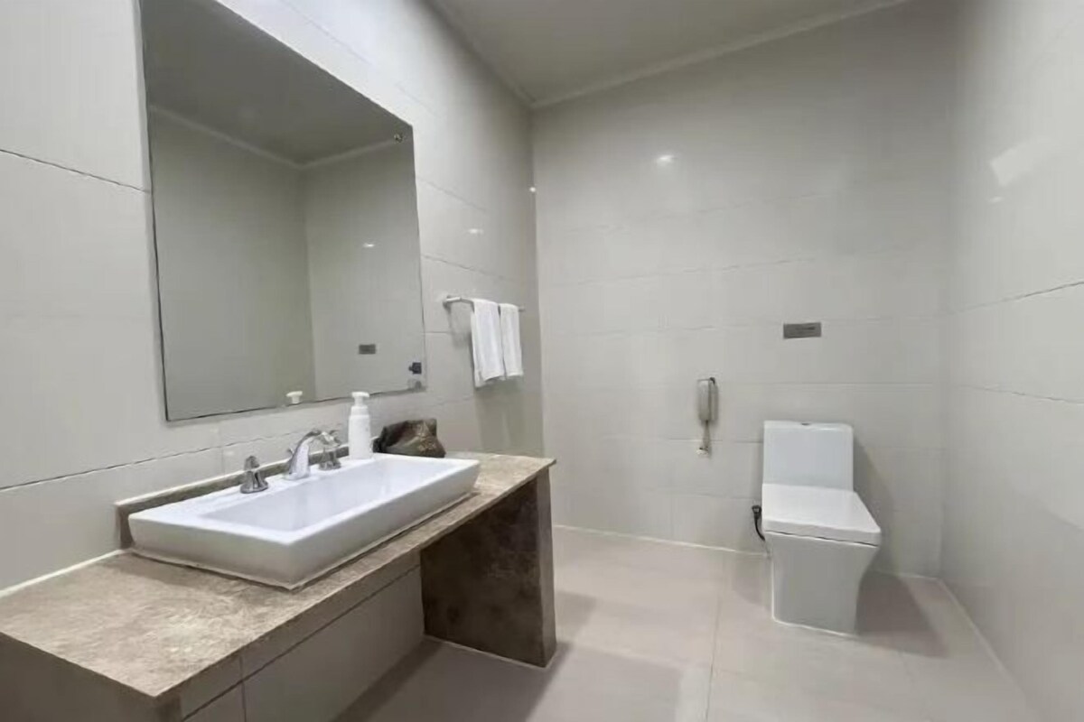 A modern bathroom with a large mirror, a sink, and a toilet.