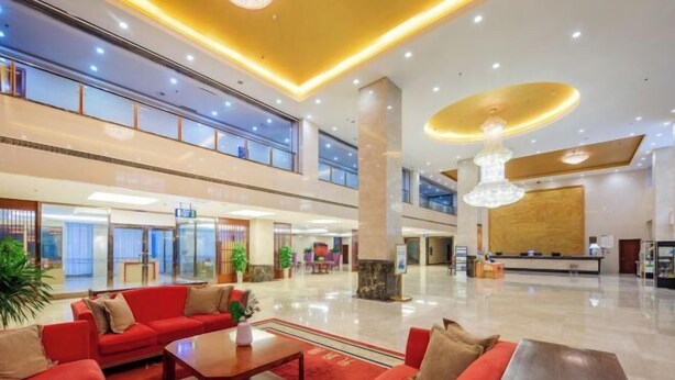 A spacious lobby with red sofas, a reception desk, and a large chandelier. - Fenghua International Garden Hotel (Dongying)