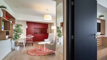 Un salon moderne avec un coin repas, une cuisine rouge et un grand miroir.