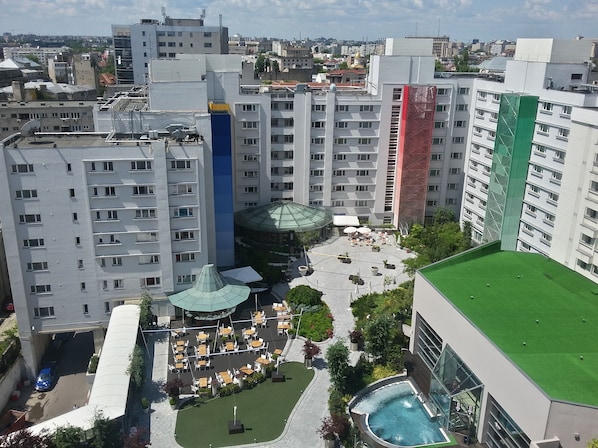 A high-rise hotel with multiple floors, outdoor seating areas, and a swimming pool.